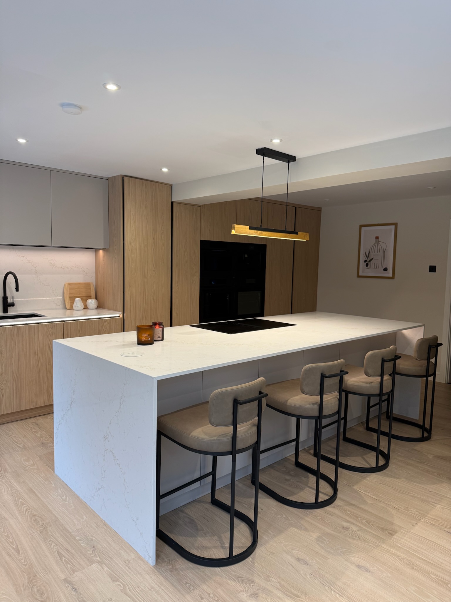 Modern open plan kitchen extension with large island, integrated appliances, wood effect cabinetry and contemporary pendant lighting Modern open plan kitchen extension with large island, integrated appliances, wood effect cabinetry and contemporary pendant lighting