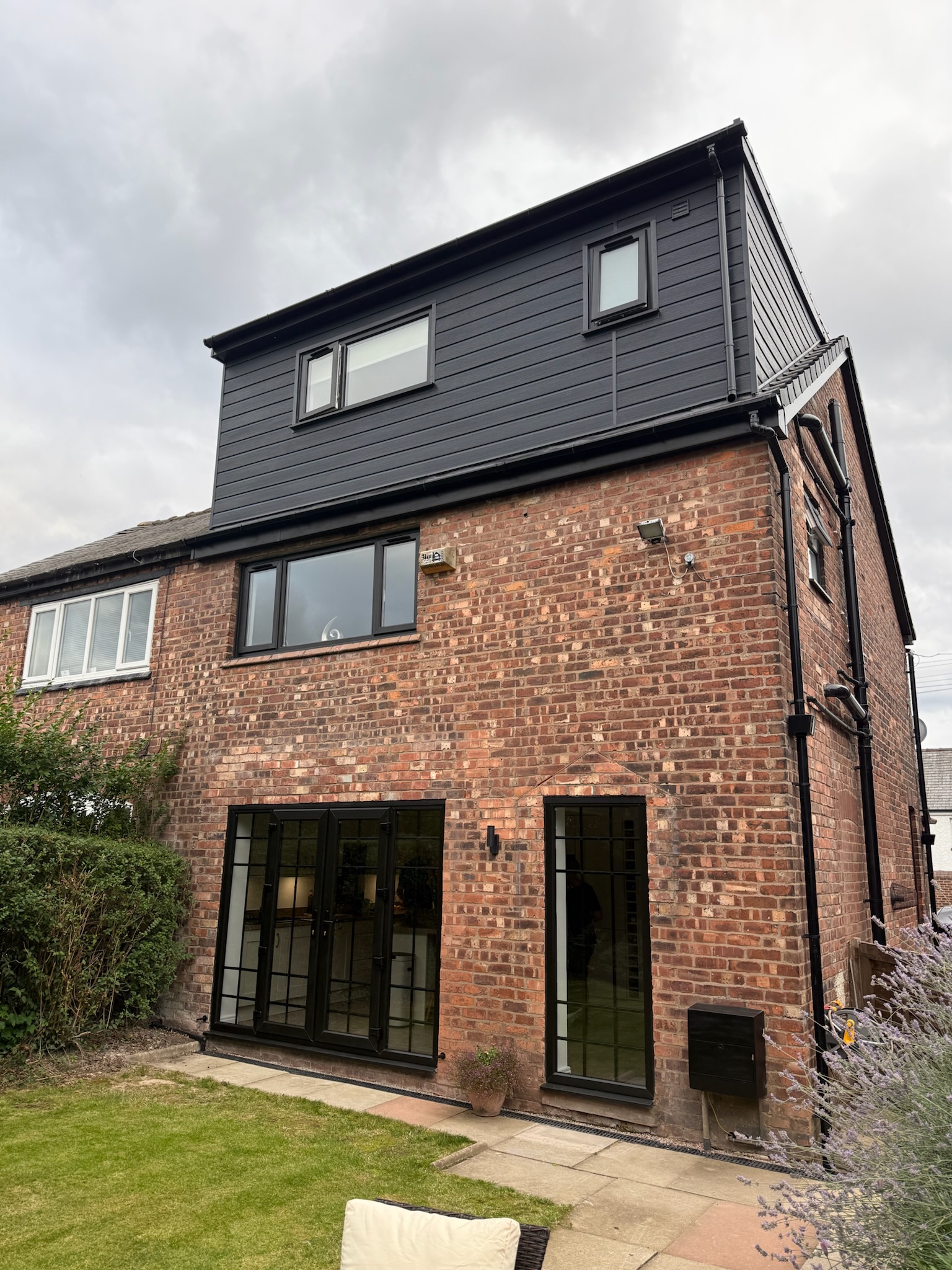 Modern loft conversion with dormer completed in Bury featuring anthracite cladding, black aluminium windows and new bedroom with en suite.