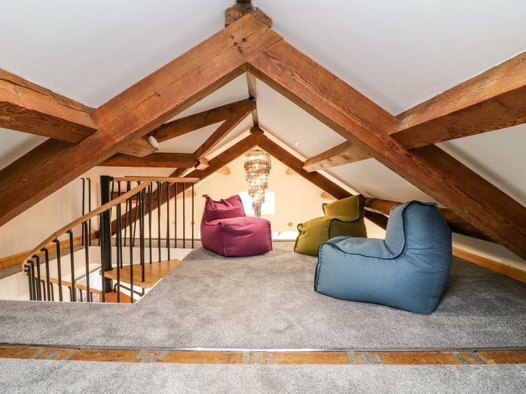 Traditional loft conversion with exposed wooden beams, staircase access and cosy loft seating area designed for extra living space