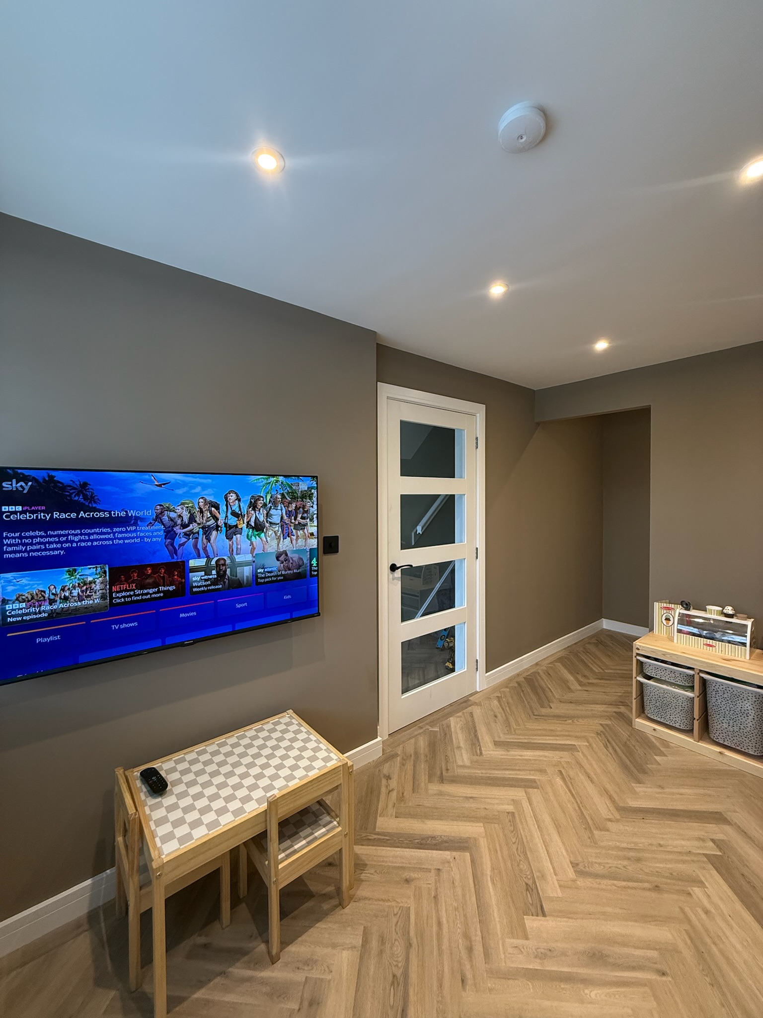 Attached garage conversion in Hyde transformed into a modern home office and playroom with herringbone flooring.