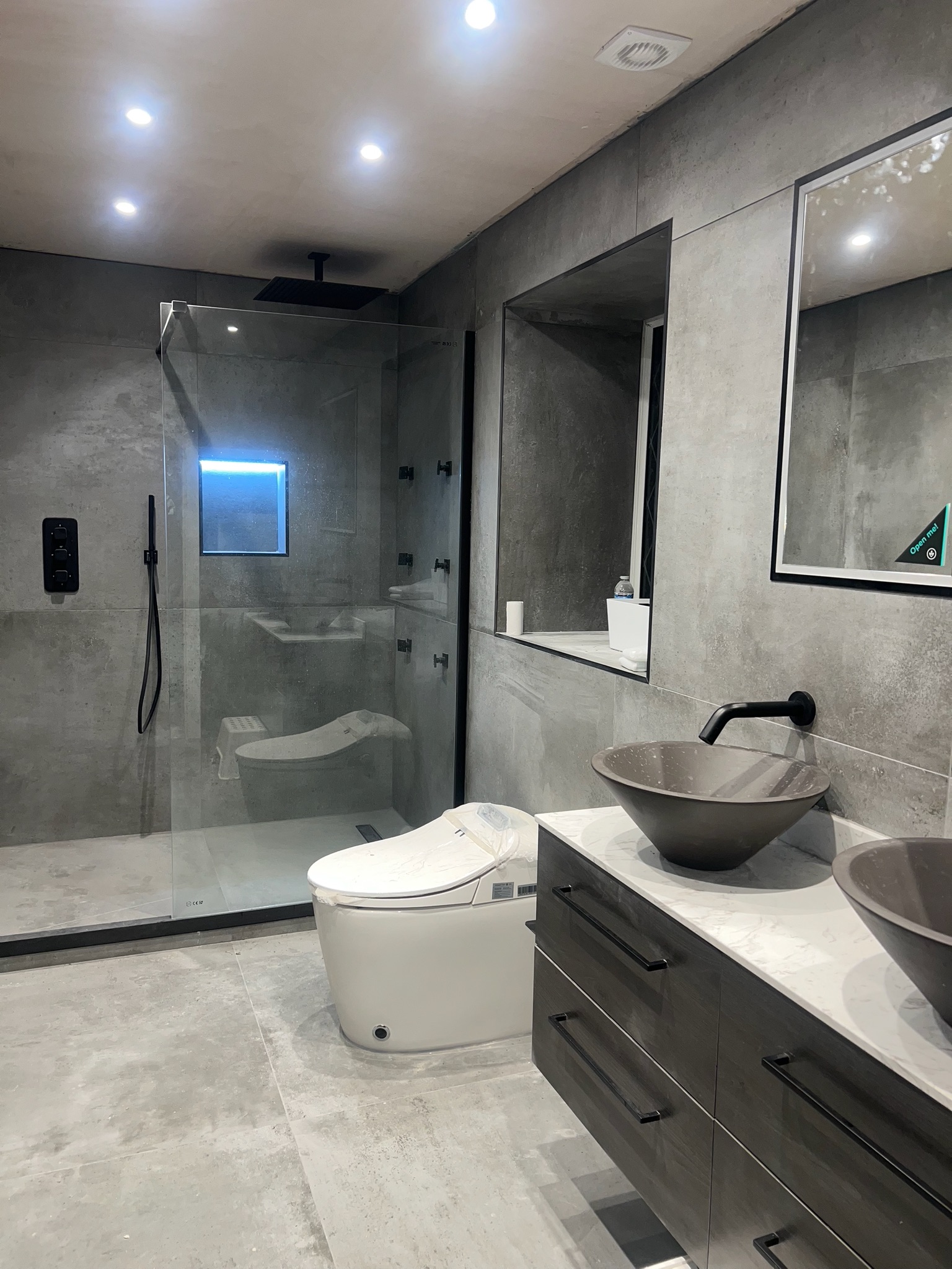 Luxury shower room completed as part of a garage conversion in Manchester with walk in shower, modern grey tiling, black fittings and double vanity unit
