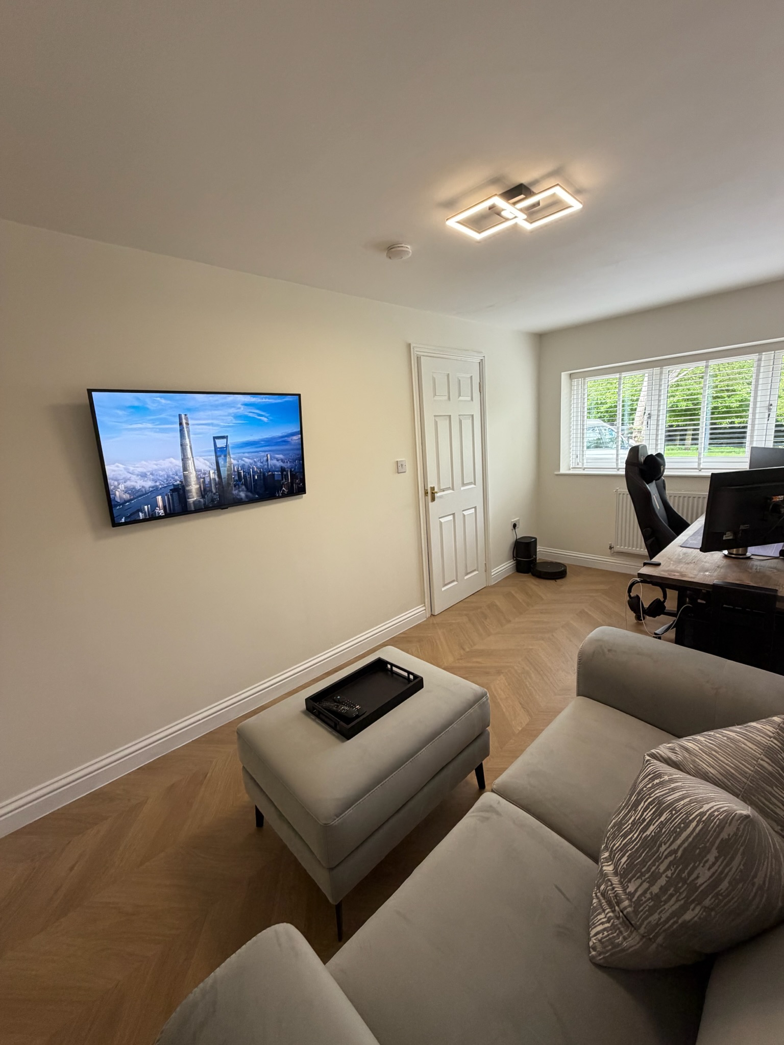 Single garage conversion in Ormskirk transformed into a multi purpose home office and snug with herringbone flooring, dedicated workspace and comfortable seating area.
