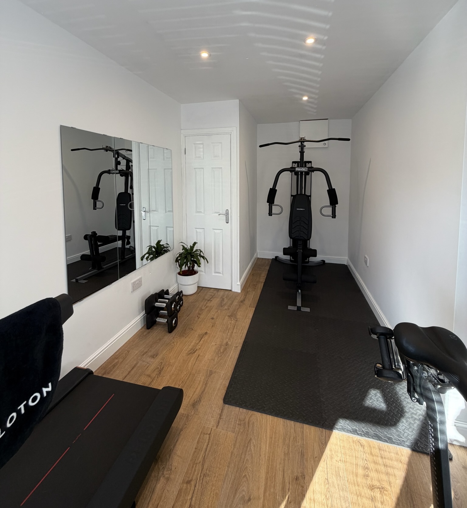 Single garage conversion in Urmston transformed into a home gym with treadmill, weights area, large wall mirror, natural light and boxed in boiler cupboard creating a clean and practical finish. Single garage conversion in Urmston transformed into a home gym with treadmill, weights area, large wall mirror, natural light and boxed in boiler cupboard creating a clean and practical finish.