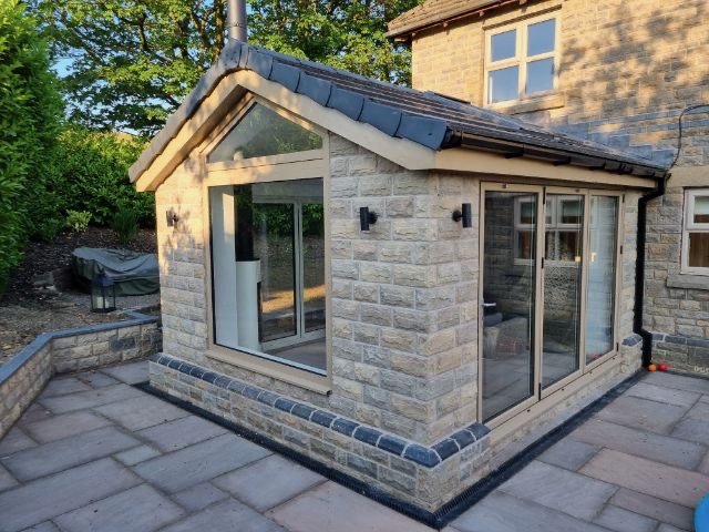 Rear extension in Rossendale featuring stone exterior, pitched roof design, large windows, sliding doors and additional open plan living space overlooking the garden.