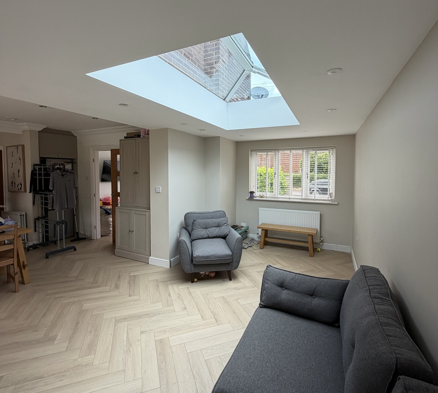 Garage conversion in Leeds transformed into a bright living space with roof lantern and herringbone flooring.