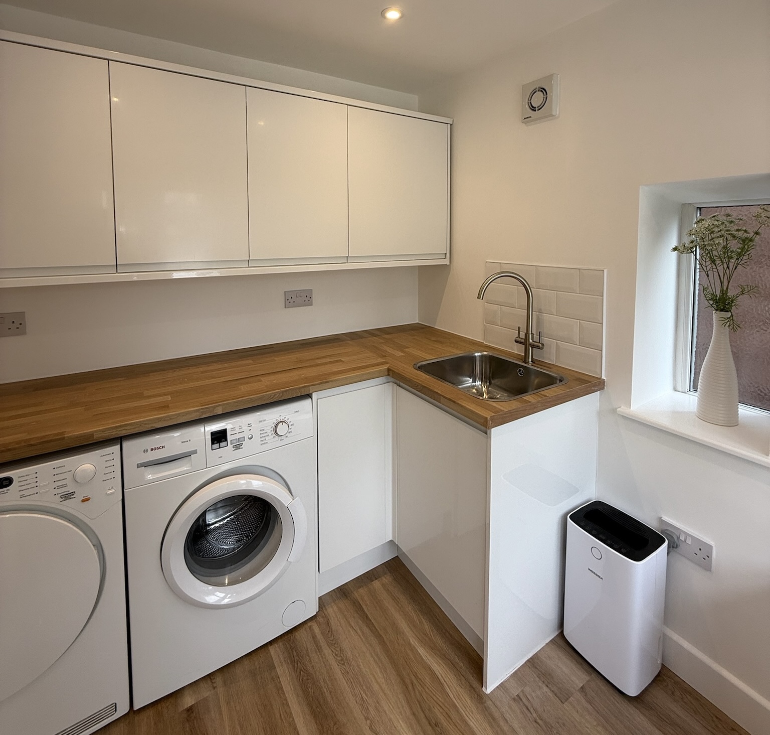 Garage utility room conversion with washing machine, tumble dryer, sink, worktops and wall storage cupboards created from a converted garage