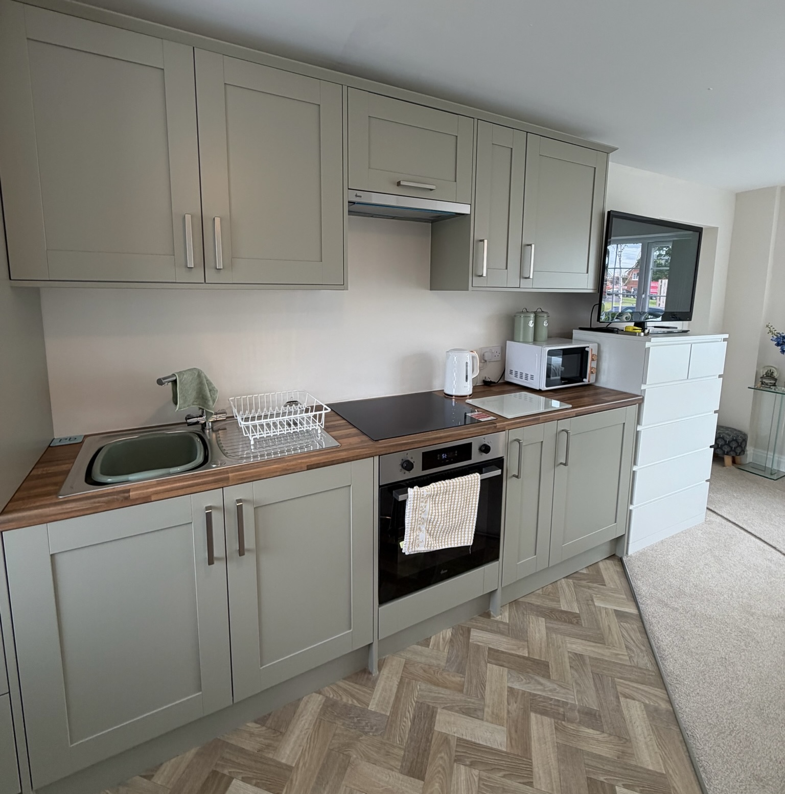 Double garage conversion in Preston featuring a utility room style kitchenette with fitted storage cupboards, sink, worktops and appliance space