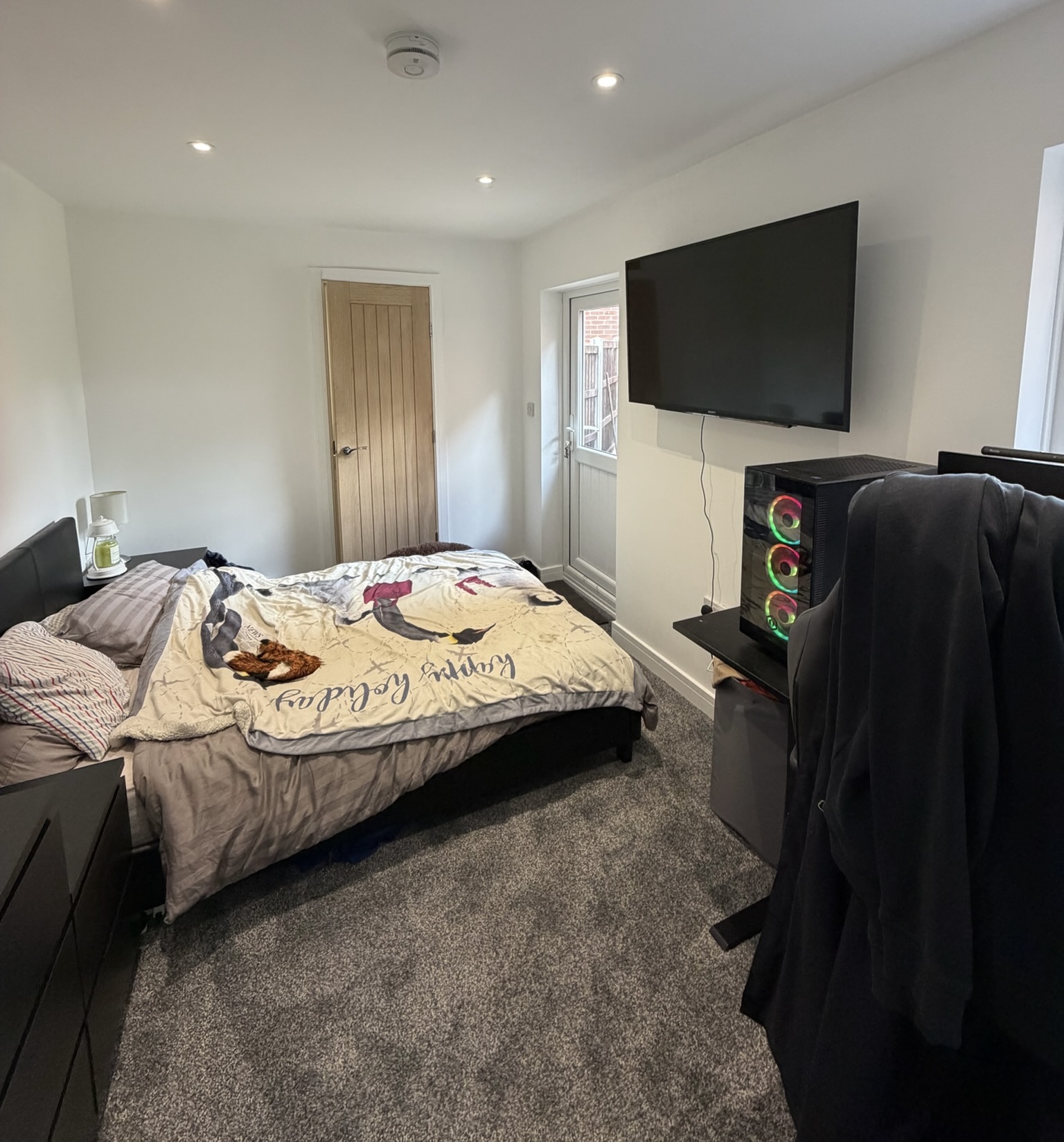 Single garage conversion in Chadderton transformed into a bedroom with en suite, featuring fitted carpet, modern lighting and direct access to the new bathroom, creating independent living space for a teenager.