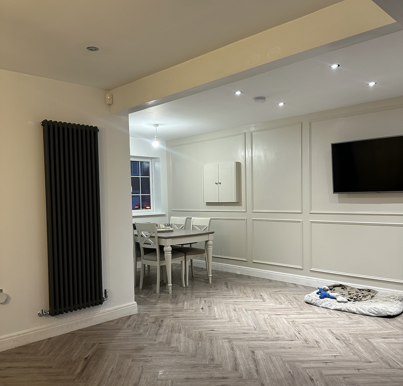 Garage conversion in Worsley creating additional open-plan living space with a dining area, wall panelling, herringbone flooring, radiator and wall-mounted television. Garage conversion in Worsley creating additional open-plan living space with a dining area, wall panelling, herringbone flooring, radiator and wall-mounted television.