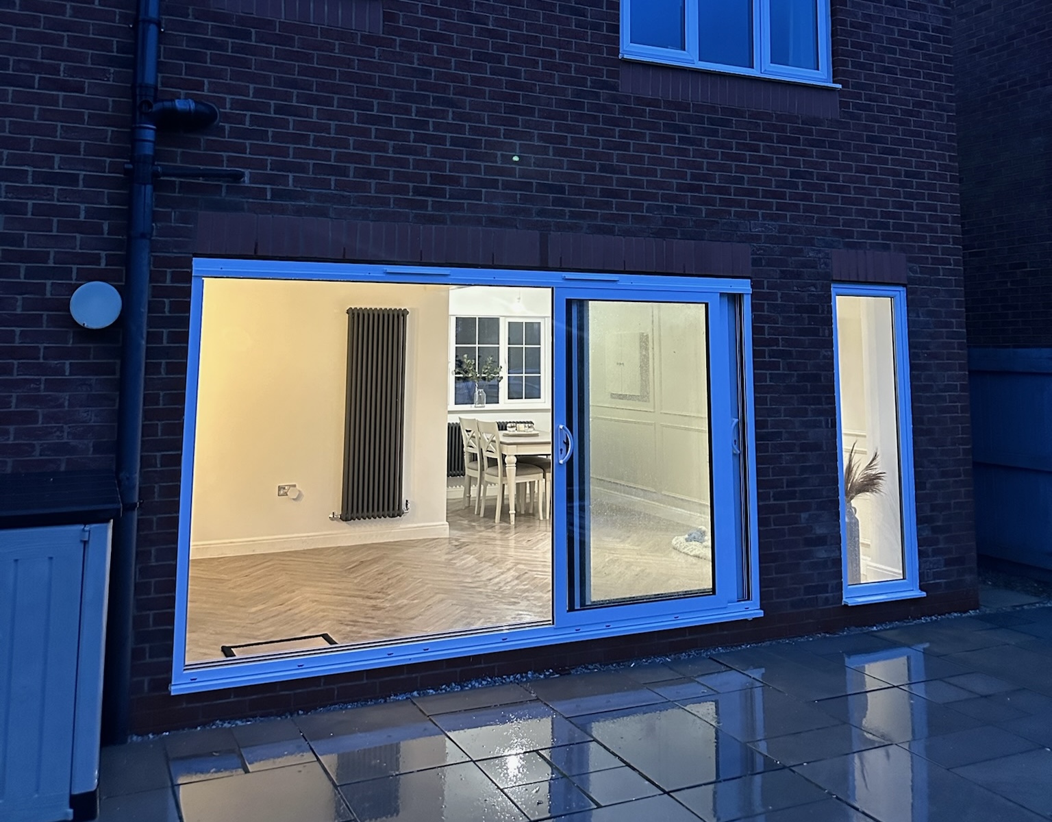 Rear view of an open plan kitchen created through a garage conversion with large sliding patio doors and full width opening.