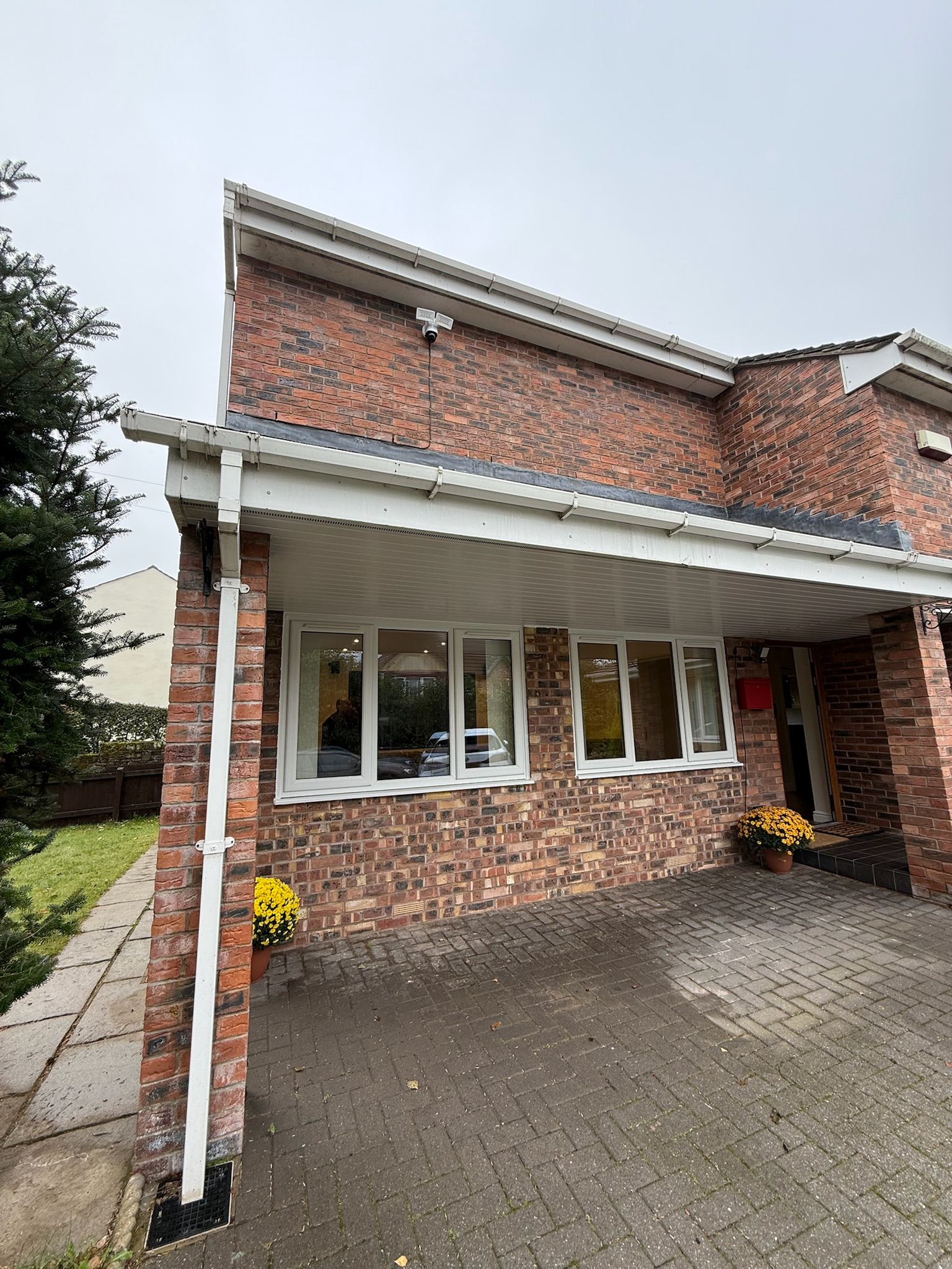 Double garage conversion in Rochdale with the original garage doors replaced by matching brickwork and white uPVC windows, creating a seamless new living space that blends with the existing home.