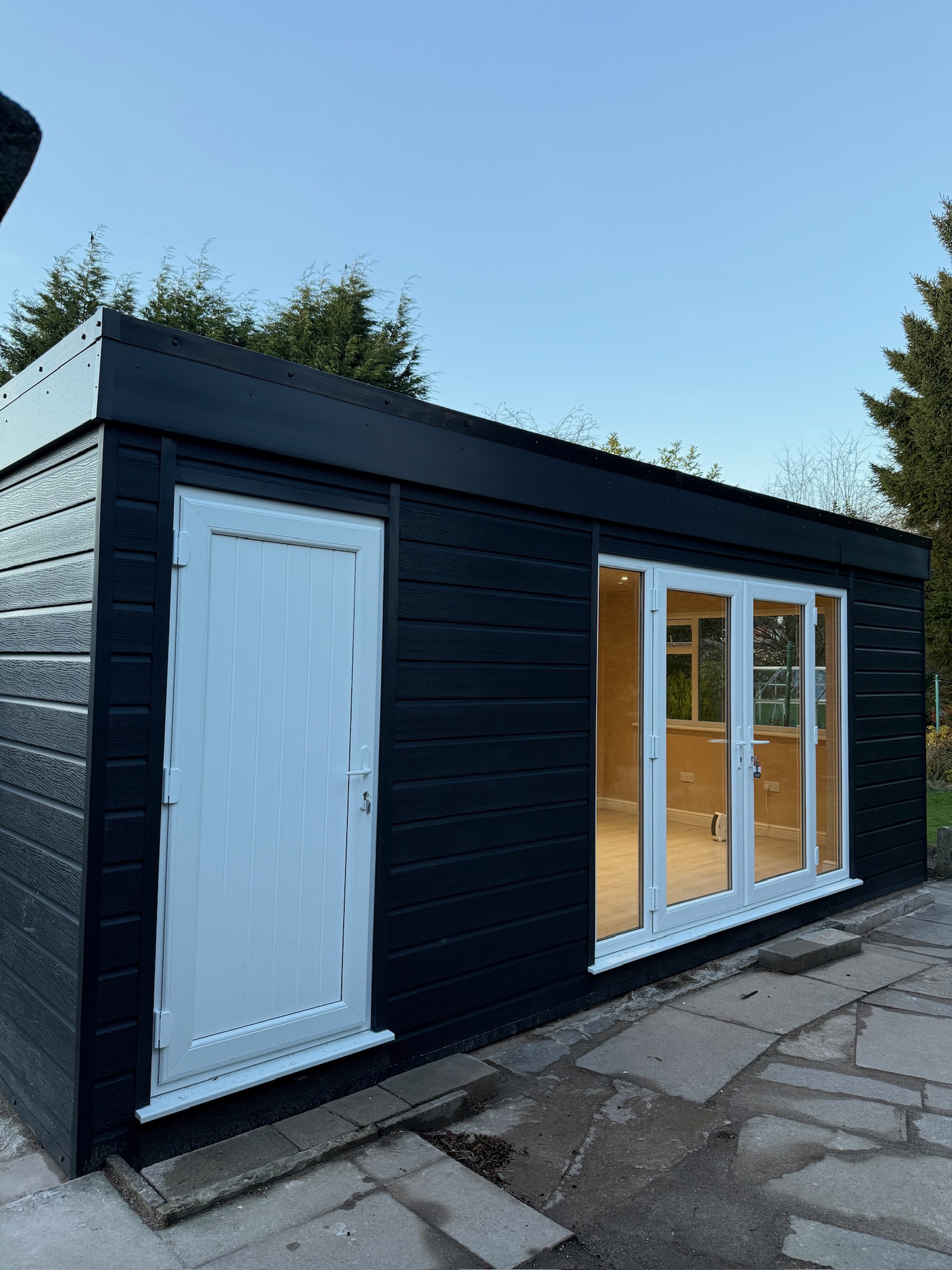 Finished garage conversion in Wilmslow with dark exterior cladding, glazed French doors and a separate access door to the converted space. Finished garage conversion in Wilmslow with dark exterior cladding, glazed French doors and a separate access door to the converted space.