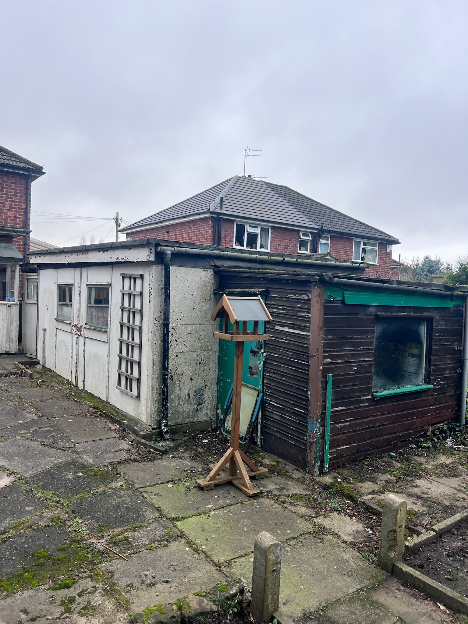 Older garage in Wilmslow before conversion showing the original exterior structure, flat roof, windows and adjoining timber section before renovation work began. Older garage in Wilmslow before conversion showing the original exterior structure, flat roof, windows and adjoining timber section before renovation work began.