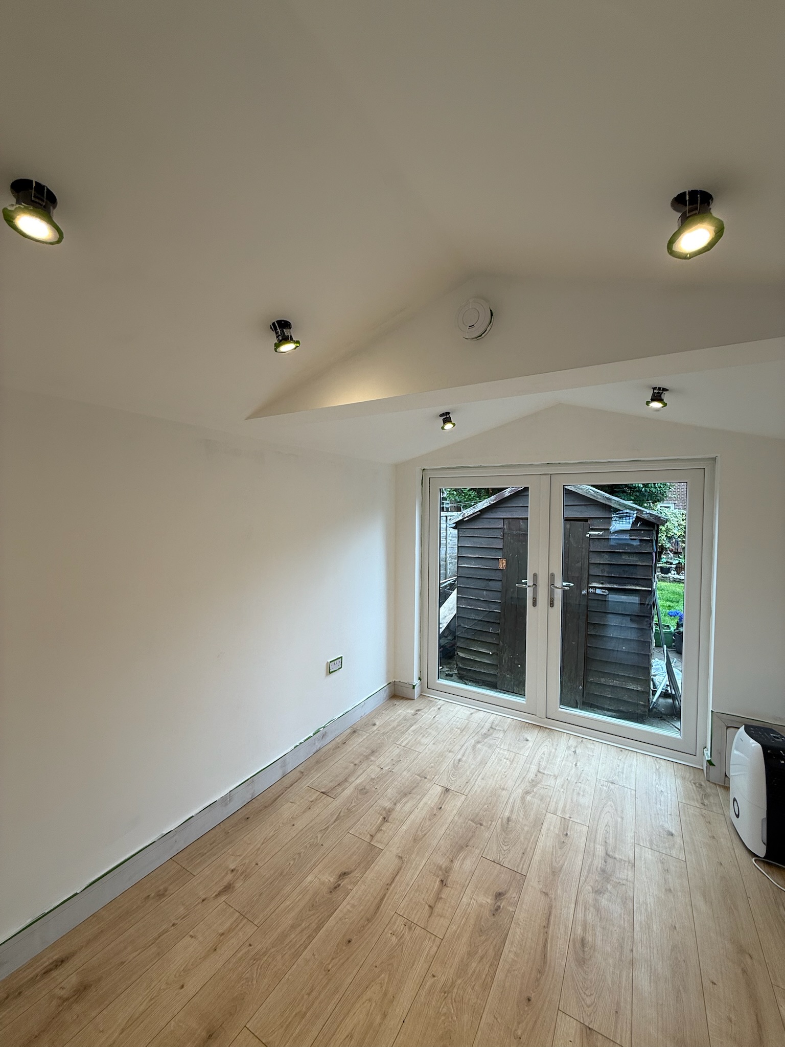 Finished interior of a prefab garage conversion in Stockport with insulated walls, flooring and French doors
