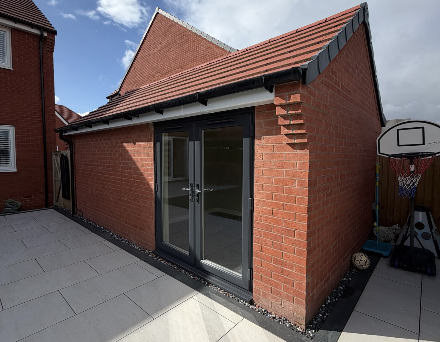 Exterior of a detached single garage conversion in Atherton with new glazed doors and part of the original garage retained for storage. Exterior of a detached single garage conversion in Atherton with new glazed doors and part of the original garage retained for storage.