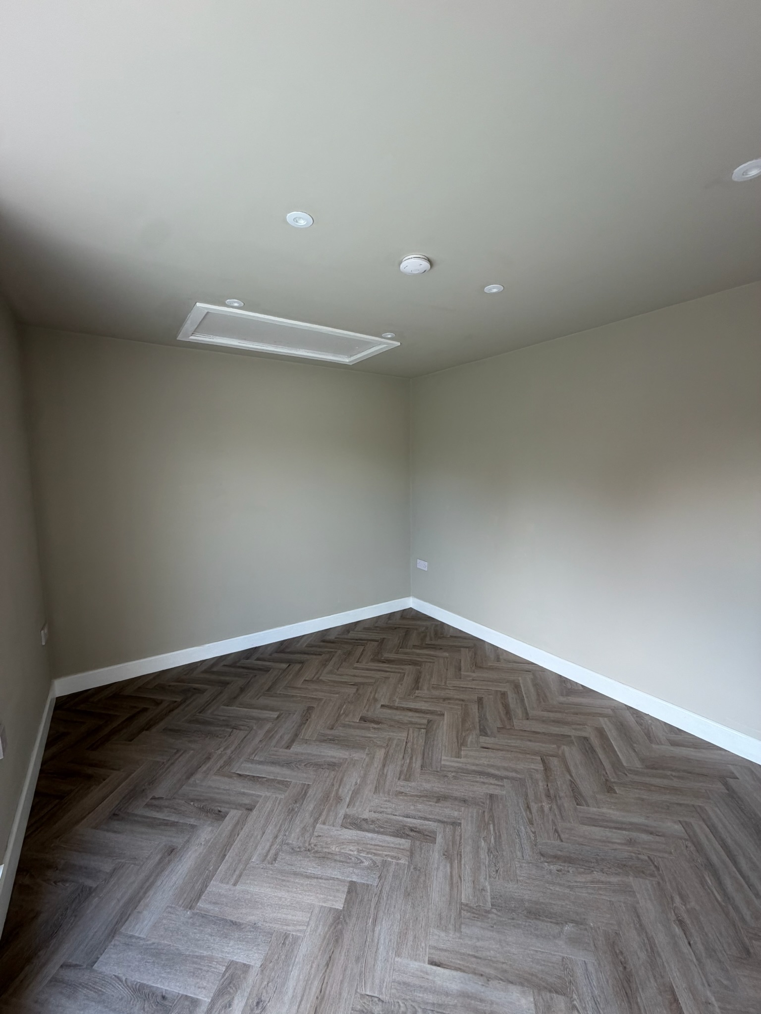 Completed single garage conversion in Wigan transformed into a finished additional room with herringbone flooring, spotlights and a loft hatch.