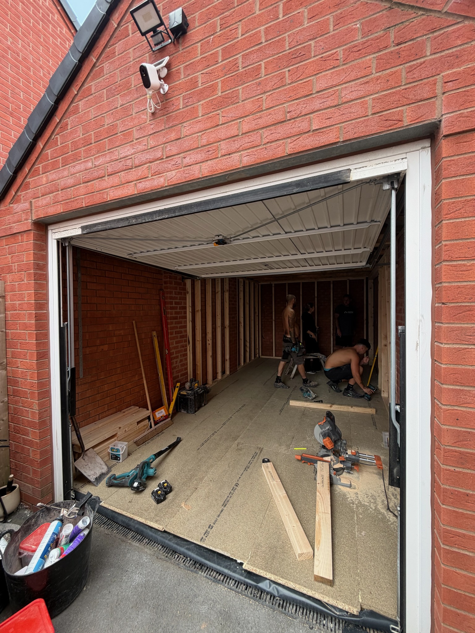 Single garage conversion in Wigan during the early construction stage, showing the original garage and new timber framework being installed.