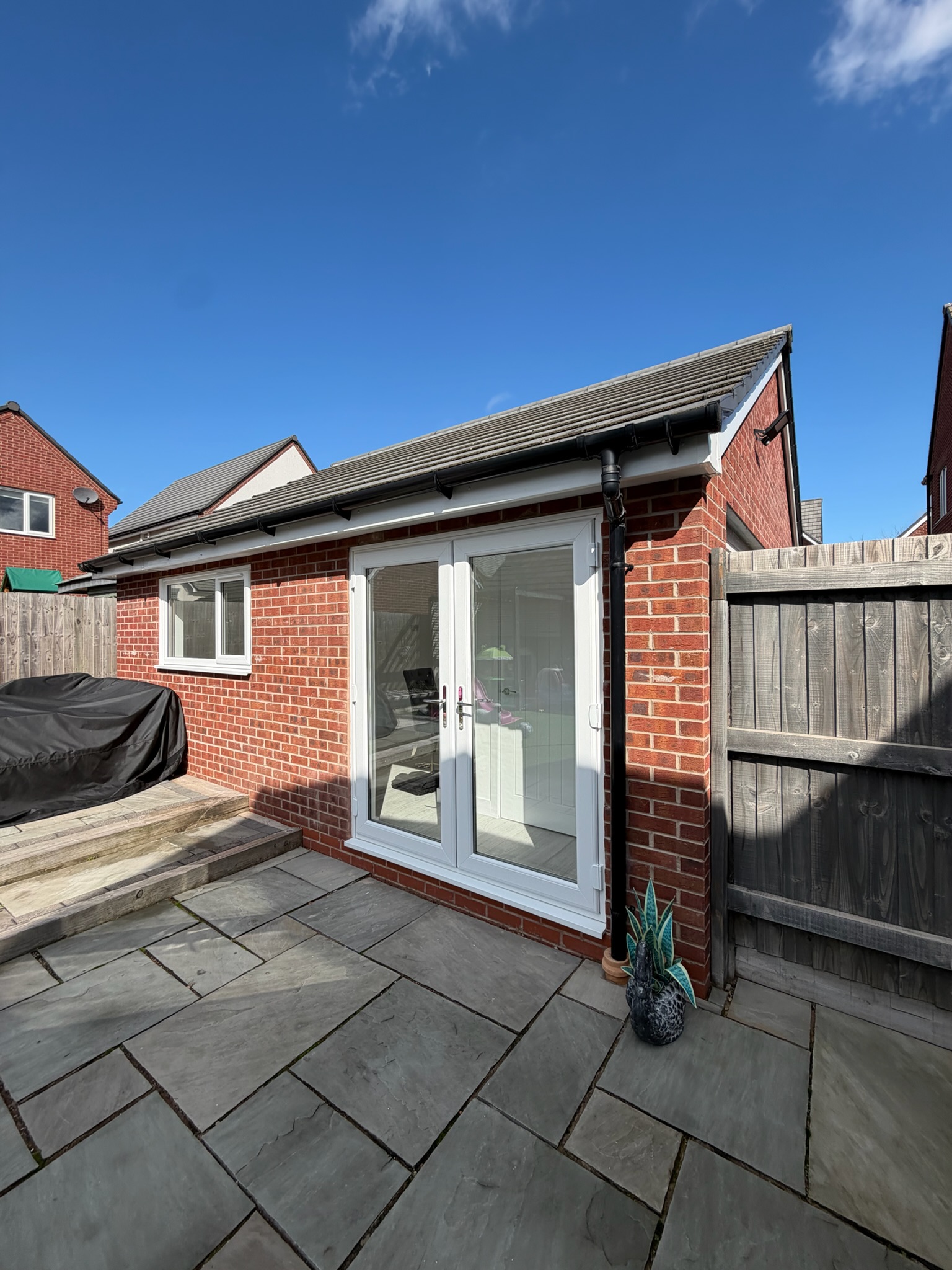 Single garage conversion in Wigan transformed into a home office with storage, featuring matching red brickwork, white French doors and a window. Single garage conversion in Wigan transformed into a home office with storage, featuring matching red brickwork, white French doors and a window.