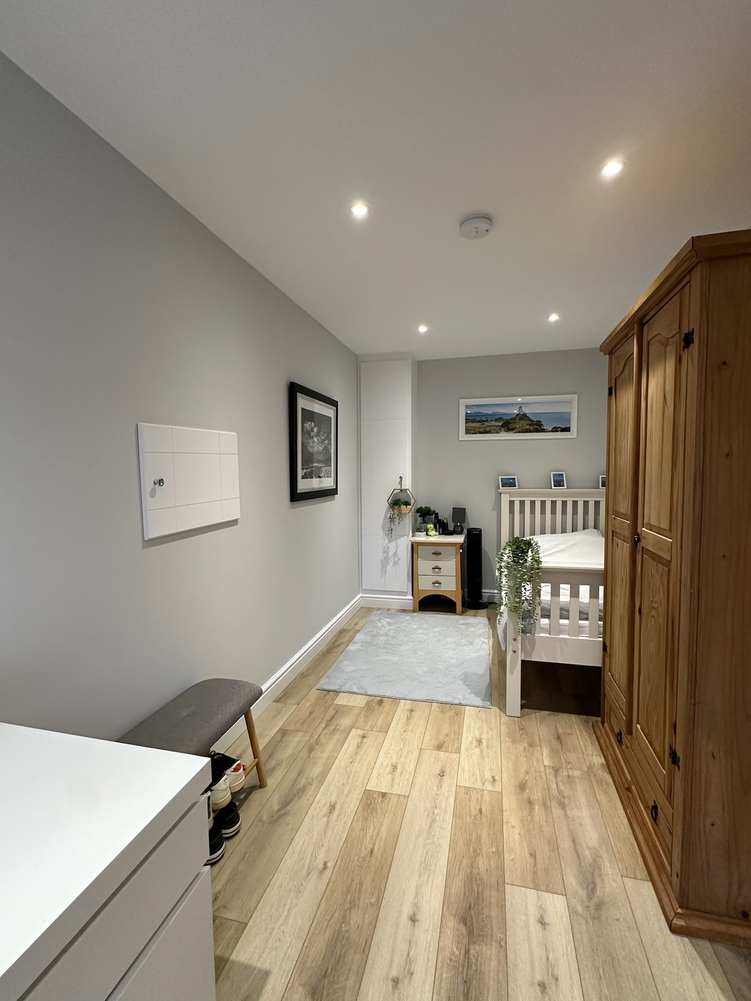 Single garage conversion in Crewe transformed into a comfortable bedroom with wooden flooring, fitted storage, ceiling spotlights and a freestanding wardrobe.