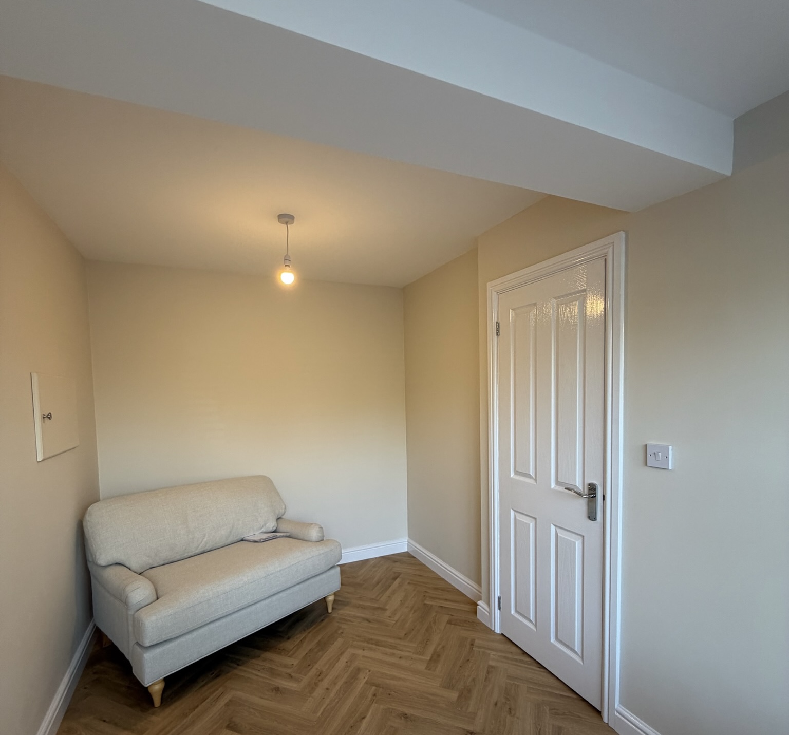 Garage conversion in Darwen transformed into a cosy snug with a small sofa, herringbone flooring, neutral walls and an internal door. Garage conversion in Darwen transformed into a cosy snug with a small sofa, herringbone flooring, neutral walls and an internal door.