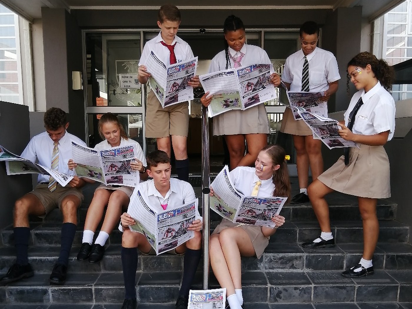 Learners at a participating school reading an AWSUM Clashes edition on the school steps