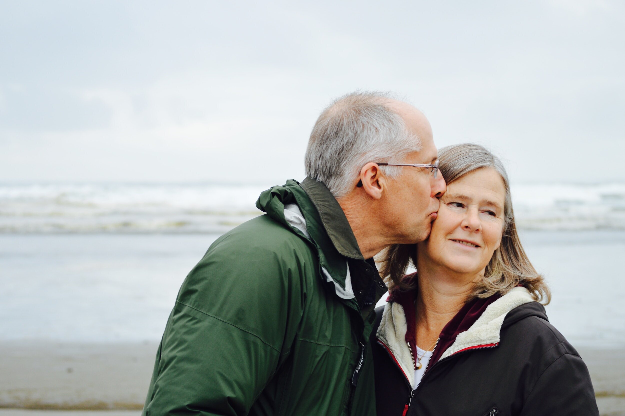 An elderly couple enjoying life together on a beach, showing that scoliosis care supports patients of all ages