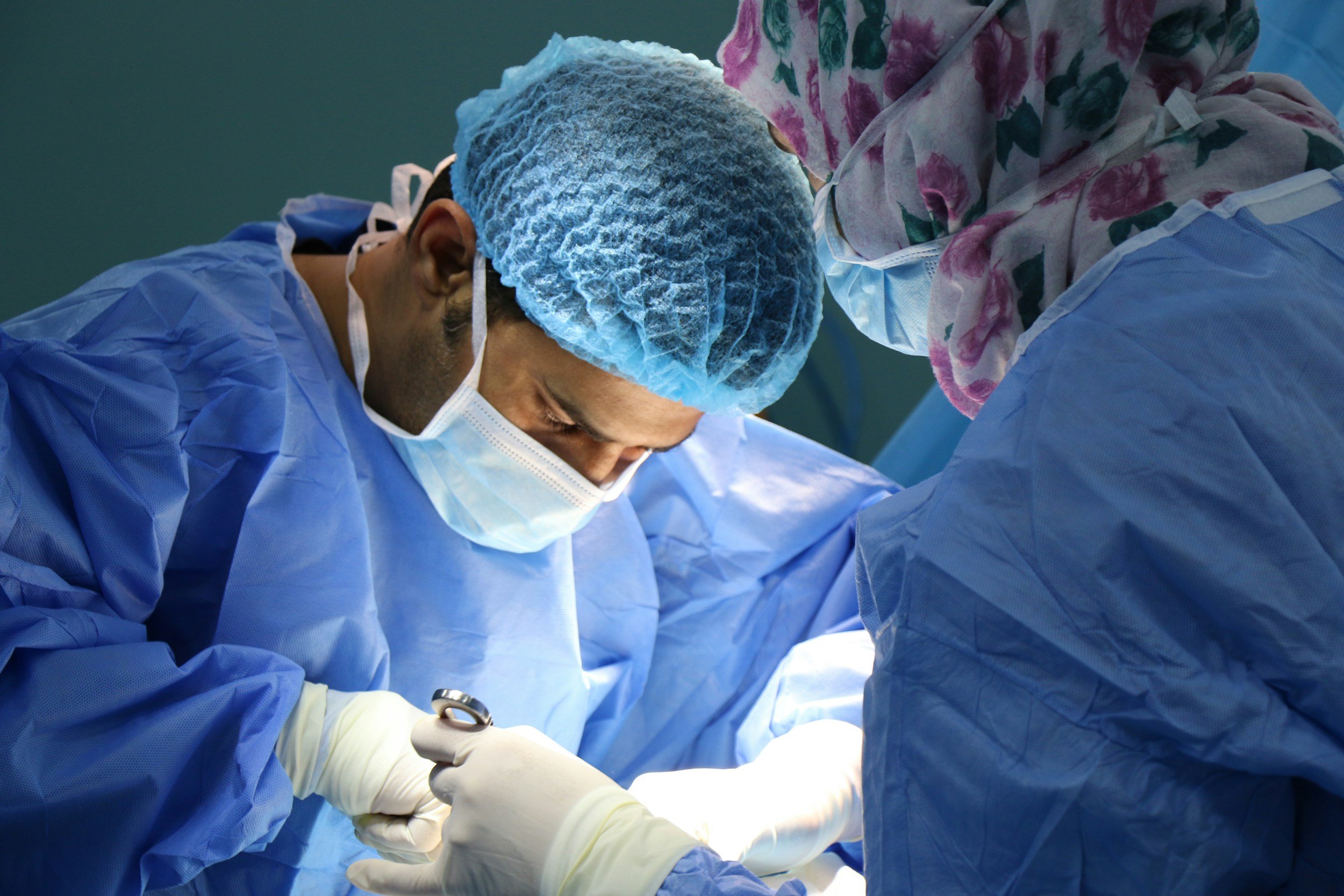 Medical professionals in surgical gear performing surgery.