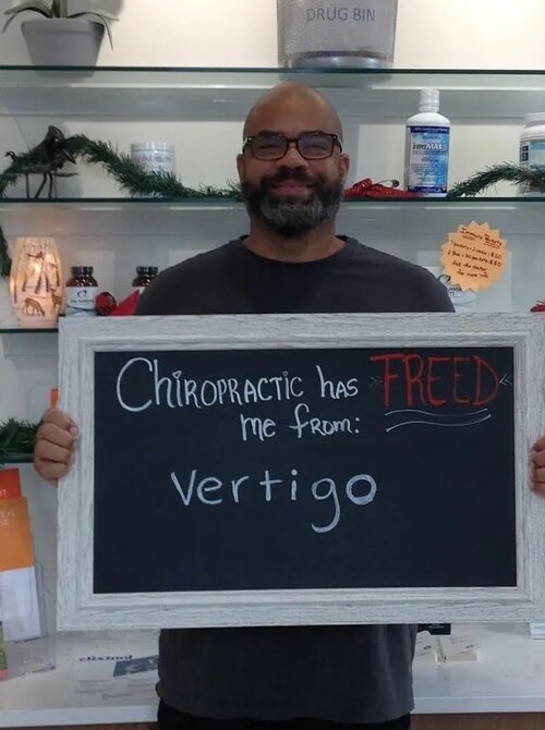 A man holding a chalkboard sign about relief from vertigo at Lake Nona Chiropractic