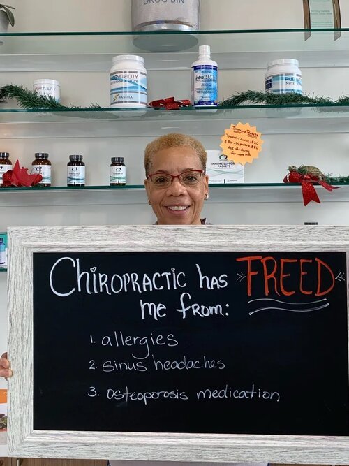 A woman holding a chalkboard sign about relief from allergies, sinus headaches, and osteoporosis medication at Lake Nona Chiropractic