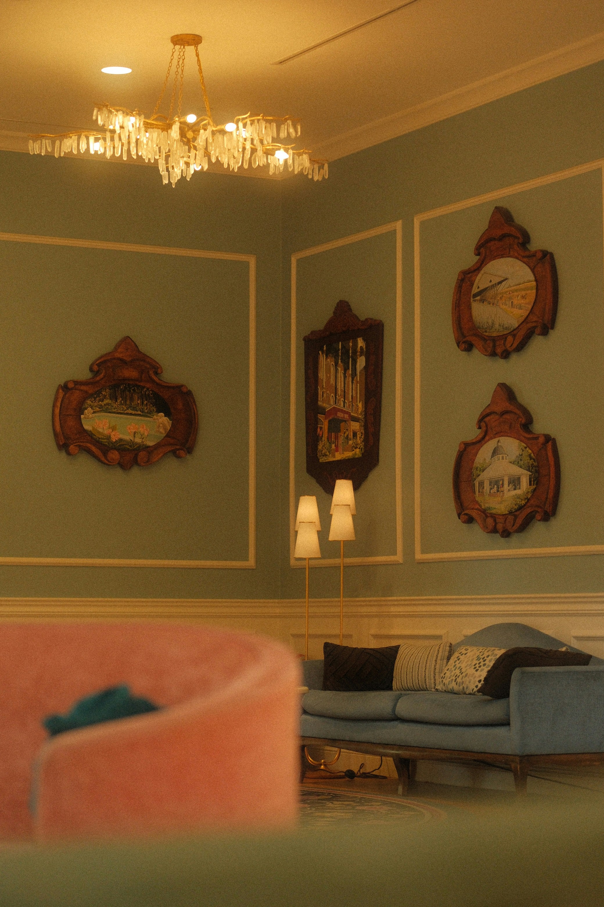 Interior designed space of a wall with framed paintings and lamps