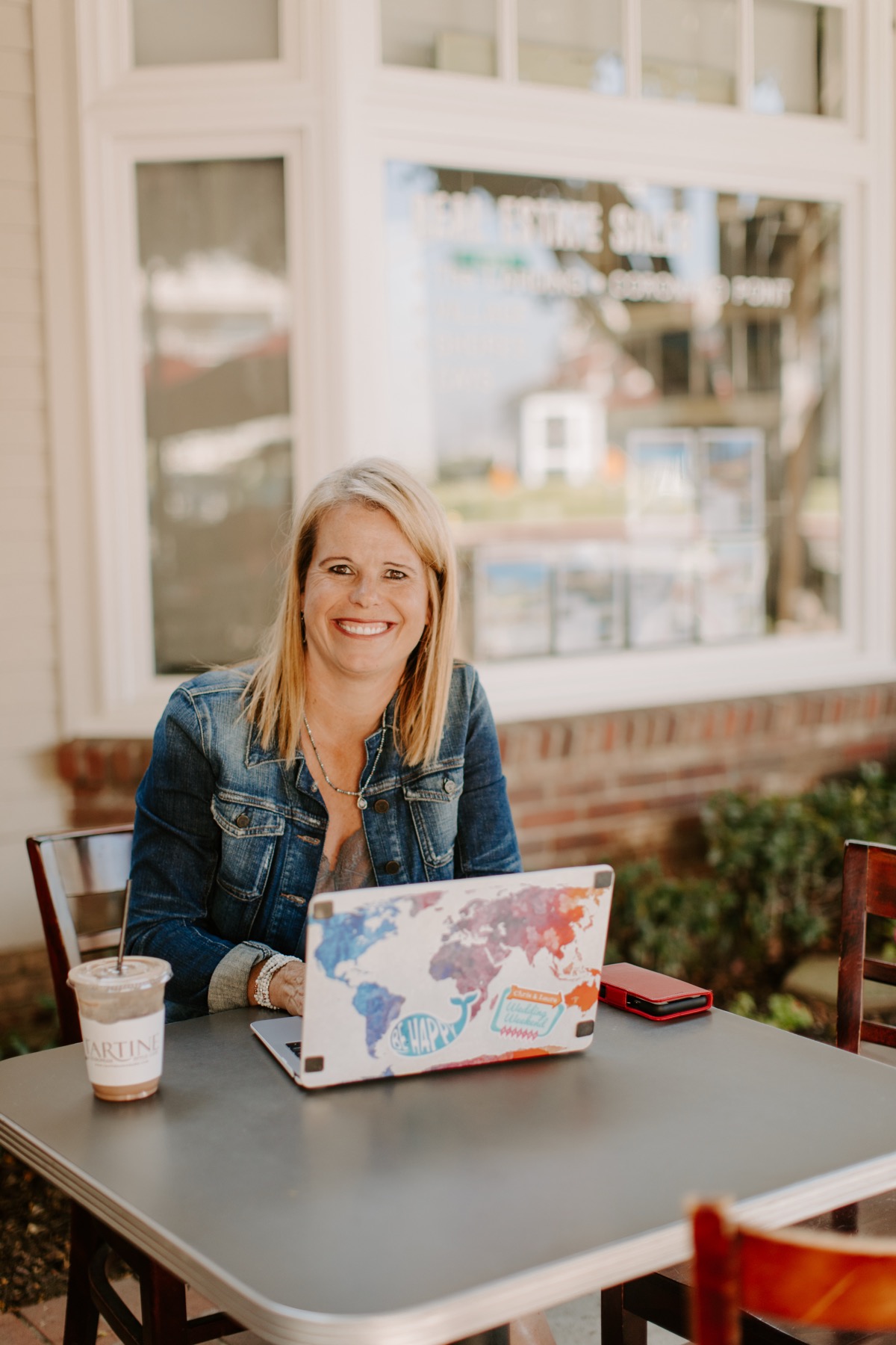 Laura Nelson smiling at her laptop at a cafe table