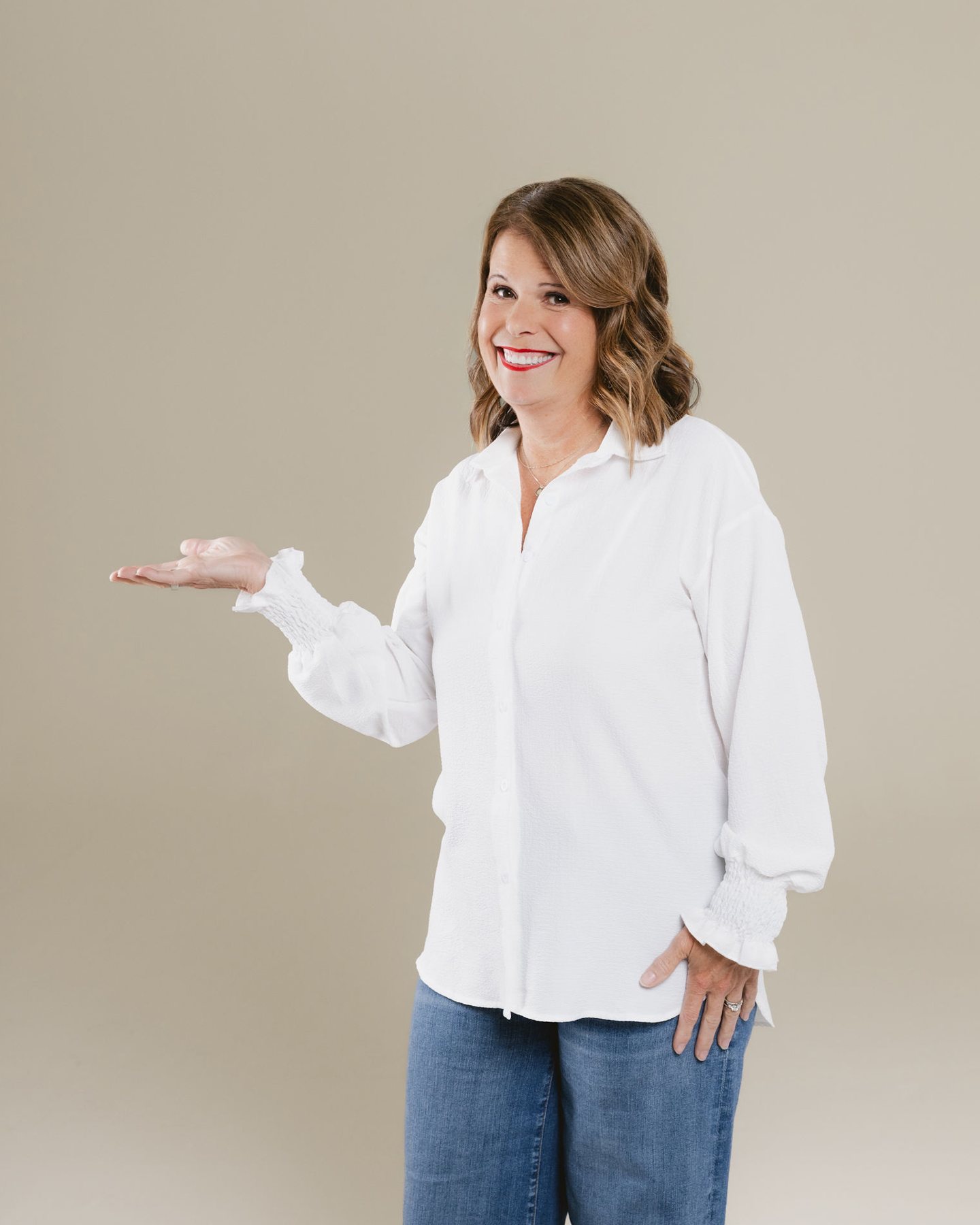 Laura Nelson smiling and holding out her hand toward the cards