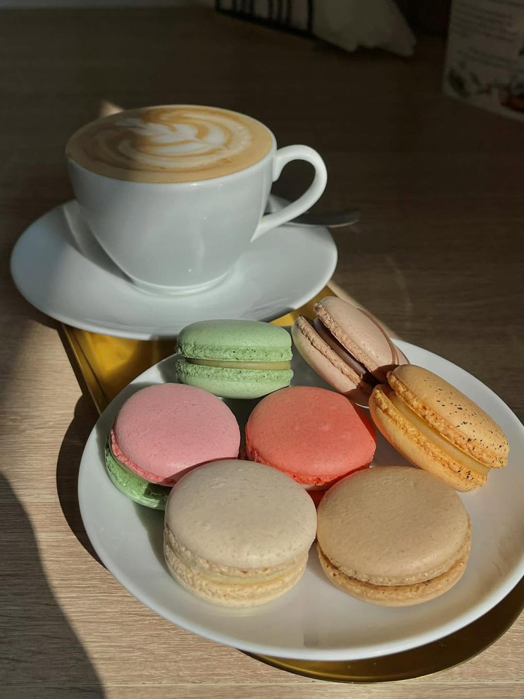 Csésze kávé és színes macaronok egy tányéron