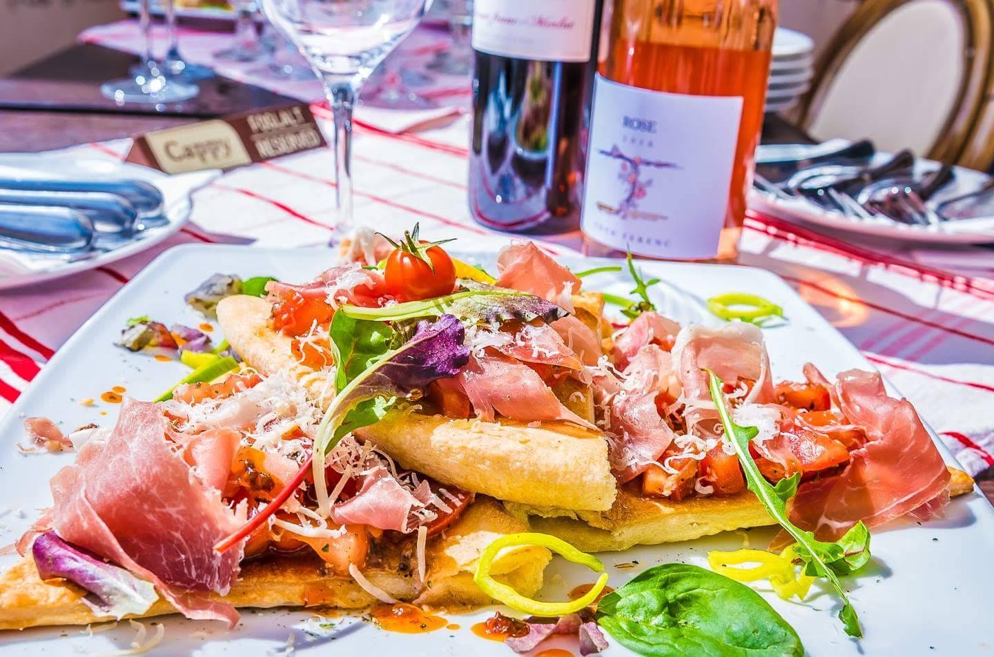 Sonkával, rukkolával és paradicsommal tálalt pizza