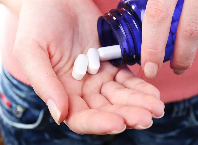Image showing a person pouring. Prescription pain pills Into his hand from a bottle .