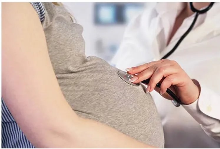 Image of a doctor examining a pregnant patient with a stethoscope on her belly As she's being treated with Suboxone during her pregnancy for opioid use disorder.