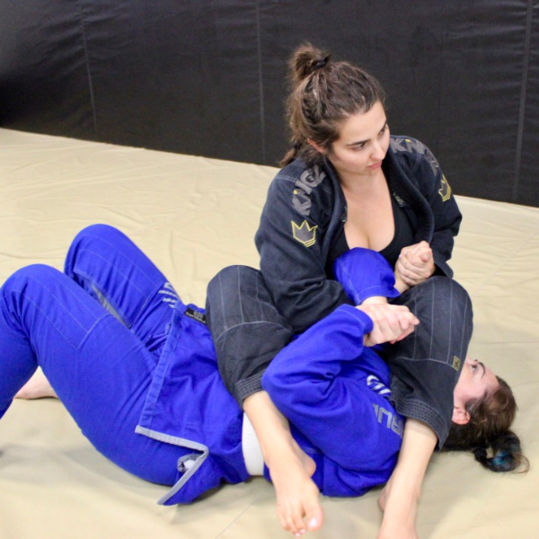 A diverse group of empowered women practicing advanced jiu-jitsu techniques under the expert guidance of a purple belt instructor at the renowned Renzo Gracie Jiu-Jitsu Academy in Weston, showcasing determination, skill, and camaraderie.