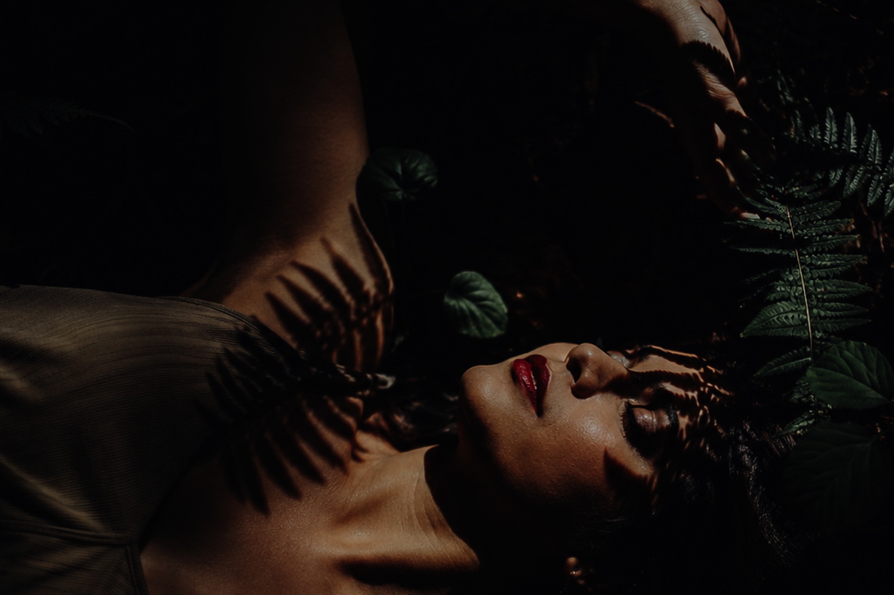 A woman resting among deep green foliage and dappled light