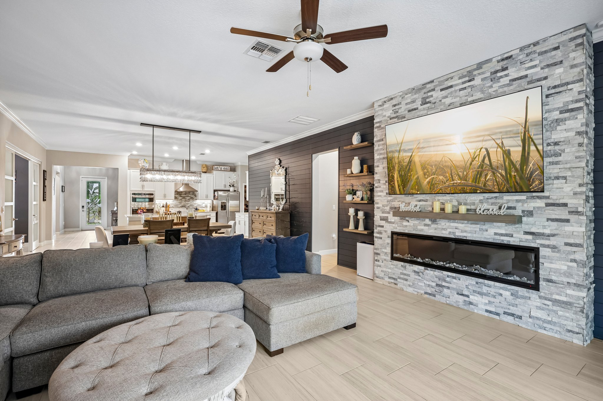 wide shot of the family room showing the stacked stone fireplace wall and navy shiplap