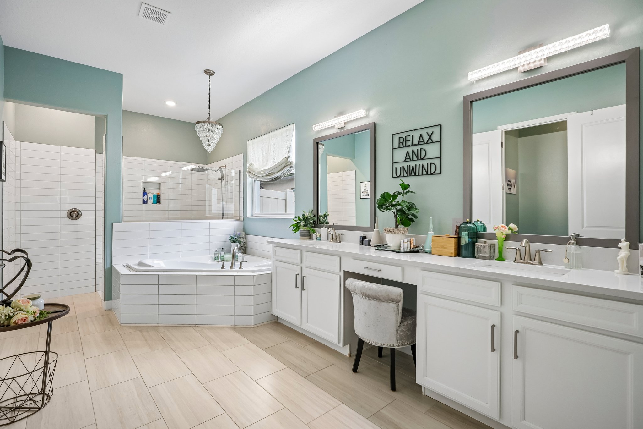 owner's bath showing the dual vanity, soaking tub, and chandelier in one frame