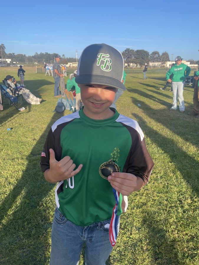 Bodhi wearing his green baseball jersey and holding a medal.