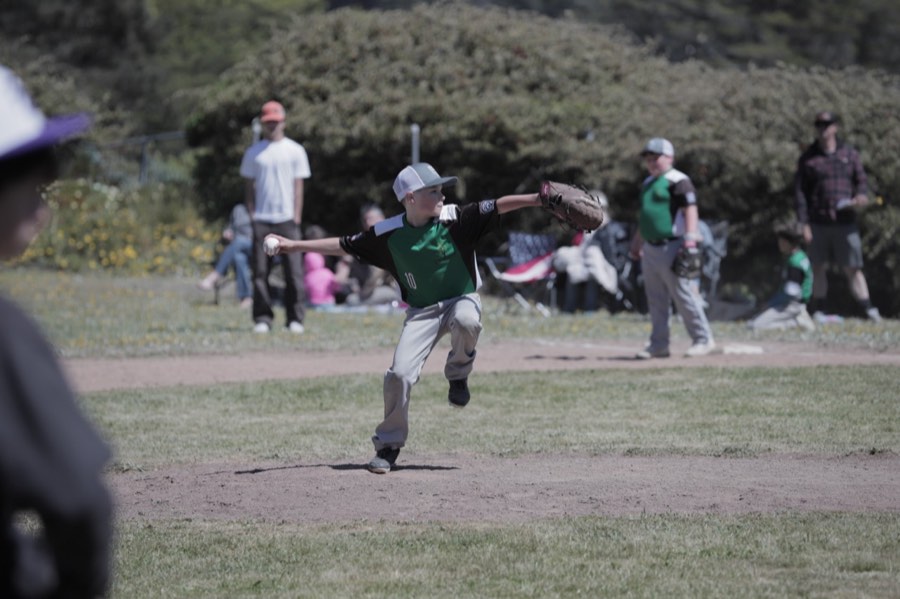 Bodhi pitching in his green baseball jersey during the 2025 season.