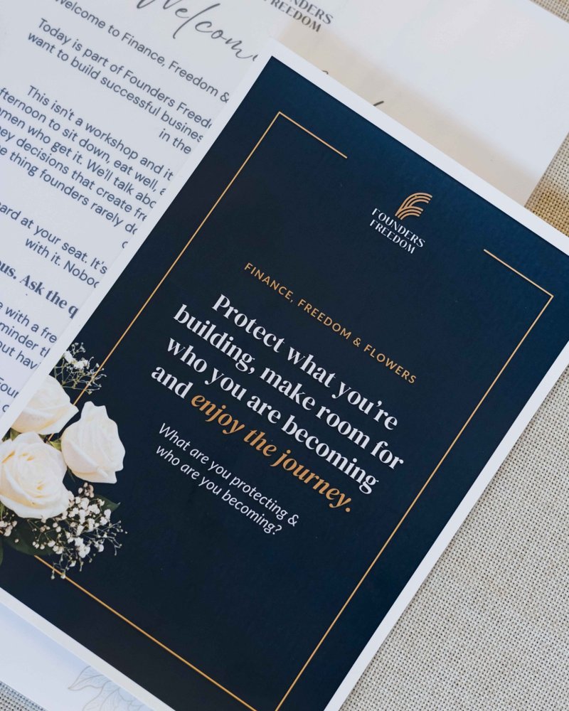 A printed Founders Freedom welcome card beside white roses