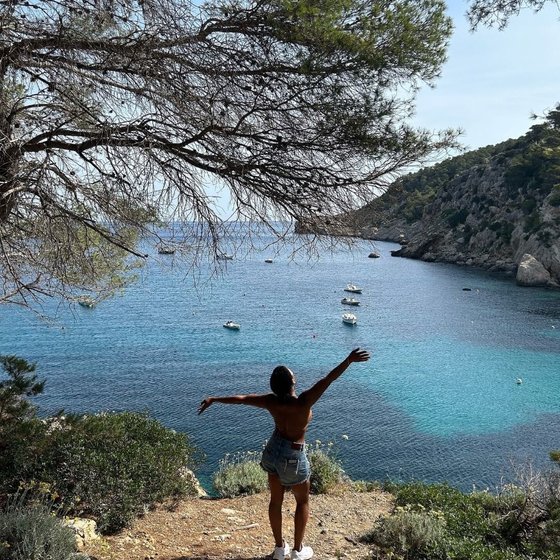 Chloe Jessamy arms outstretched above a turquoise bay