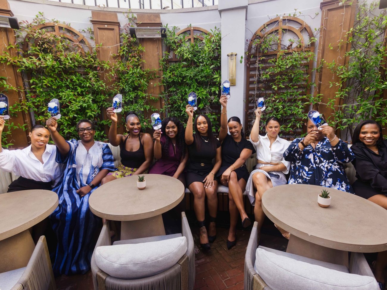 Founders seated on a garden terrace raising their Founders Freedom rose cards in the air