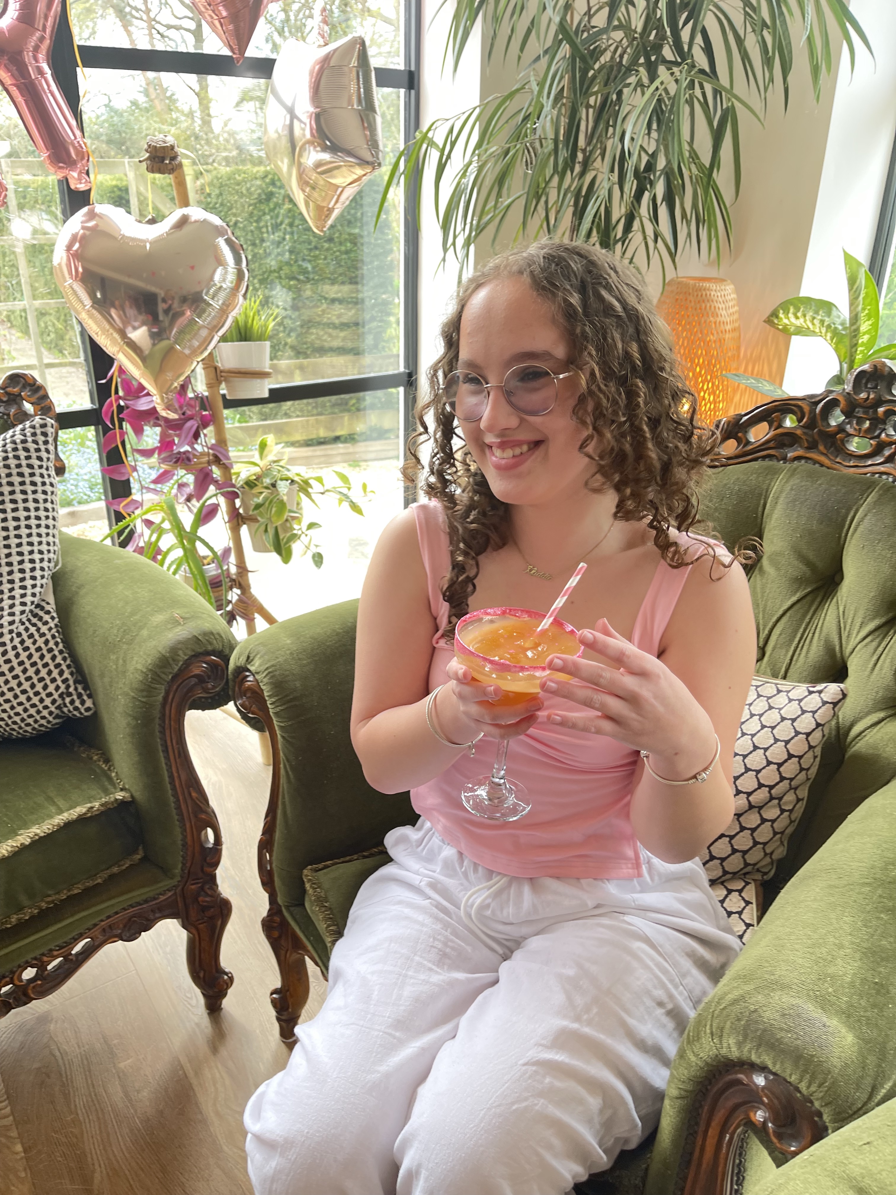 A hand holding a yellow balloon against a yellow wall