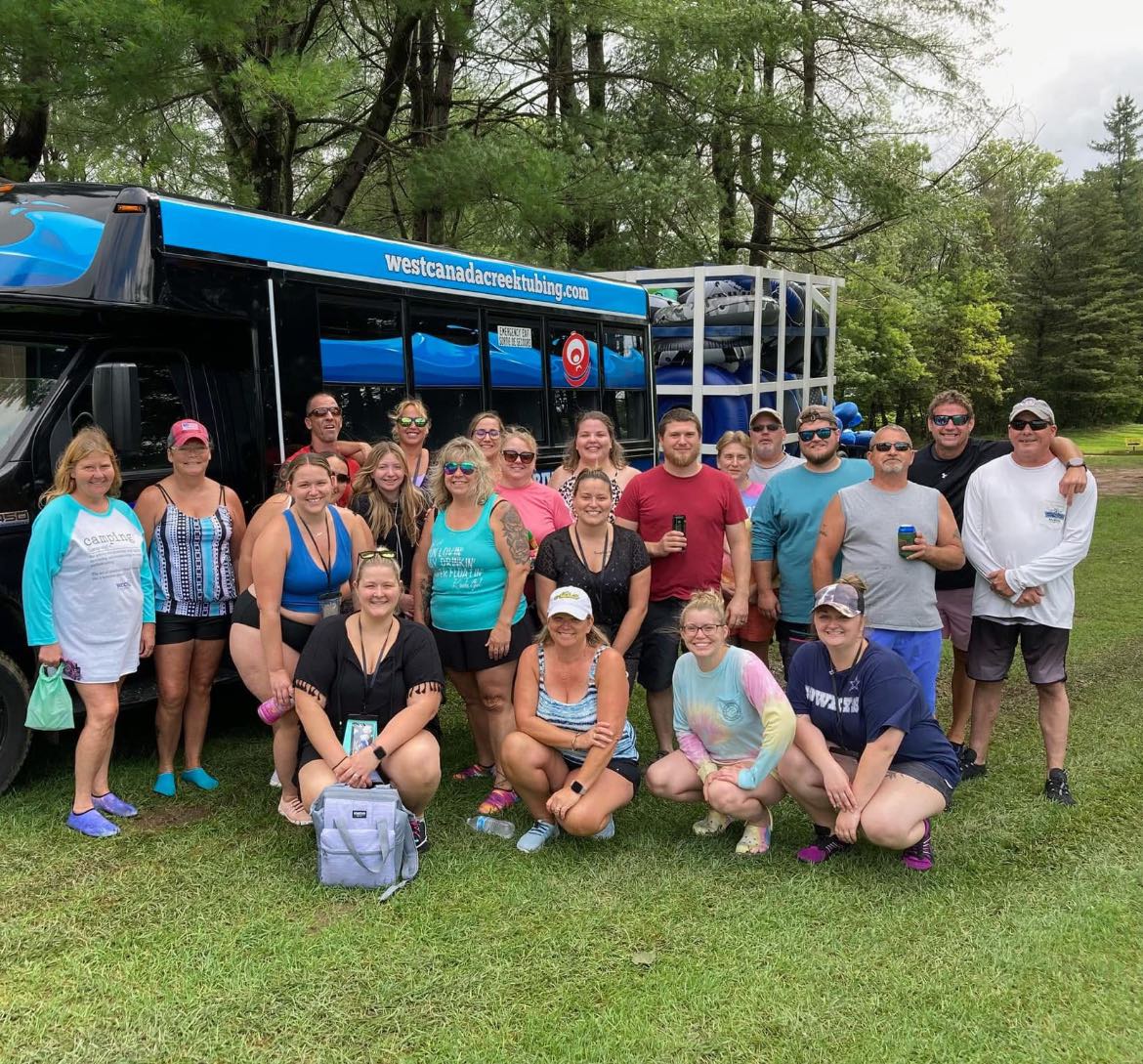 Large group of guests gathered in front of the West Canada Creek Tubing shuttle bus ready for their river adventure