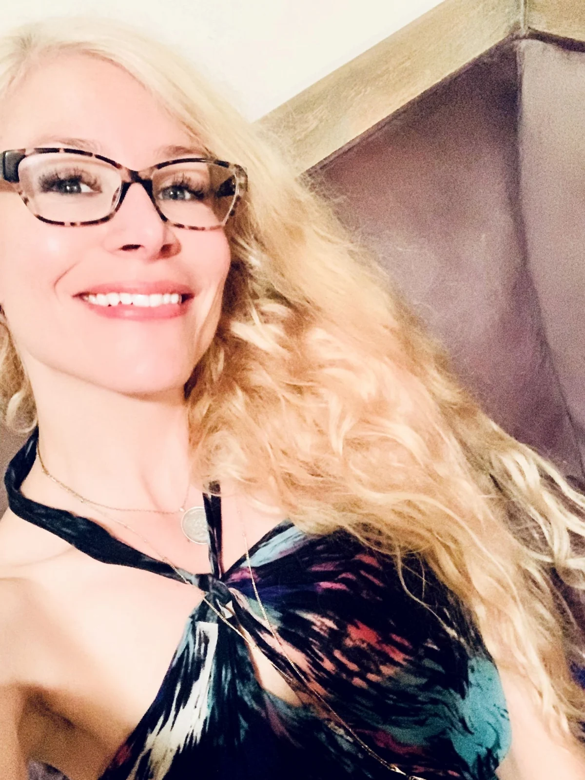 Molly Rose Holmes in tortoiseshell glasses, long curled blonde hair, smiling