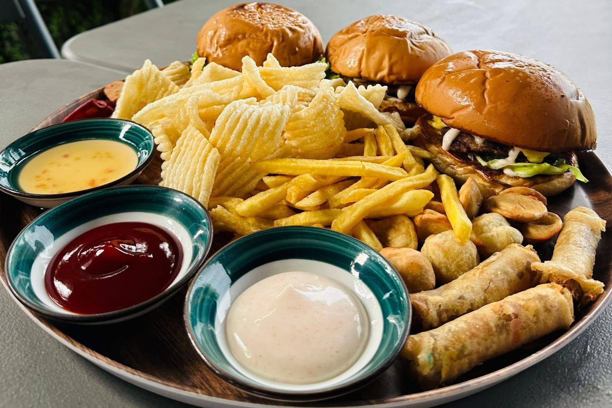 Burgers, fries, spring rolls, and dipping sauces