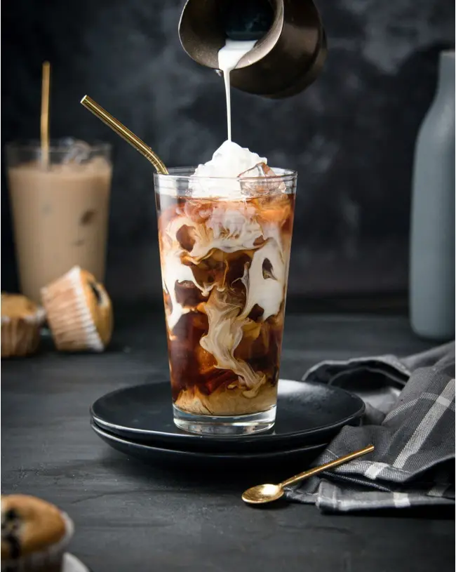 Iced coffee with milk swirling through espresso